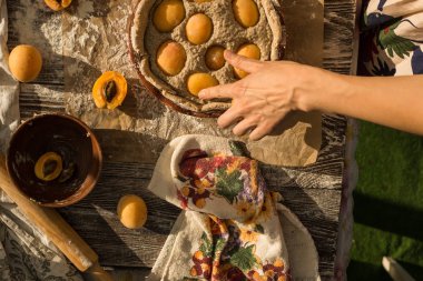 Yumuşak elbiseli kadın taze kayısılı tatlı bir turta pişiriyor.