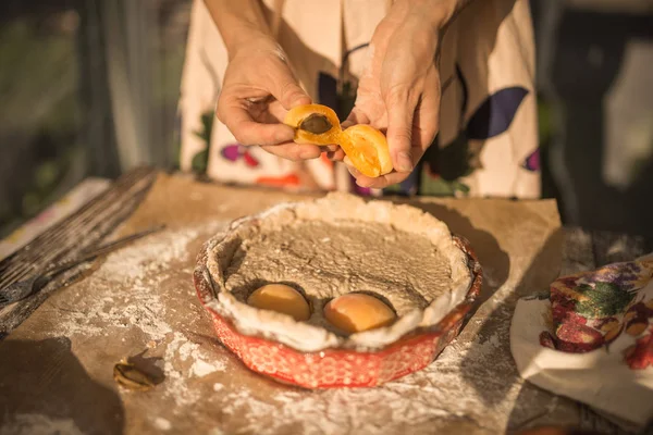 Mulher em vestido de verão doce cozinhar uma torta doce com damascos frescos — Fotografia de Stock