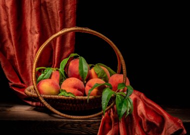 Hasır sepet ve siyah arka planda güzel şeftaliler.