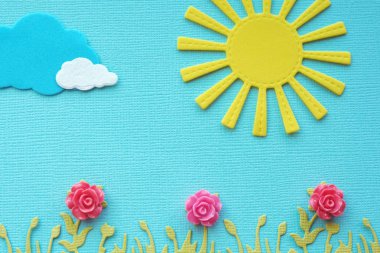 aplike parlak sarı güneş, bulutlar, çim ve ahşap çiçekler mavi dokulu kağıt üzerinde. parlak yaz konsepti. kopyalama alanı