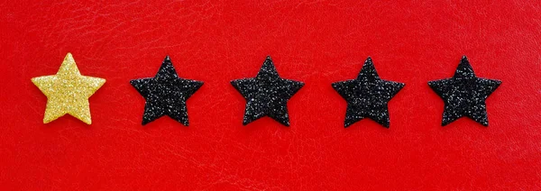 one gold rating star and four black ones on a red background.