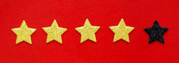 four gold rating stars and one black on a red background