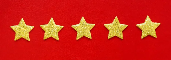 five gold rating stars on a red background.