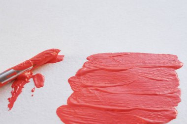 beyaz suluboya kağıt ve boya bir fırça üzerinde mercan rengi sıvı boya darbeleri. kopyalama alanı.