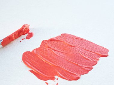 beyaz suluboya kağıt ve boya bir fırça üzerinde mercan rengi sıvı boya darbeleri. kopyalama alanı.