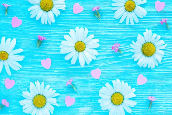 蓝色木制背景上的雏菊花 小粉色花和塑料粉色心形图案 — 图库照片