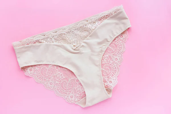 浅粉色背景的米色蕾丝女式内裤 — 图库照片