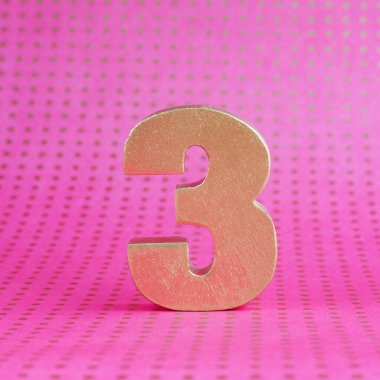 Pembe benekli parlak arka planda 3 numaralı altın hacim. Boşluğu kopyala