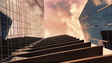 Bottom up view of skyscrapers with clouds floating above them with yellow orange alarming sky.