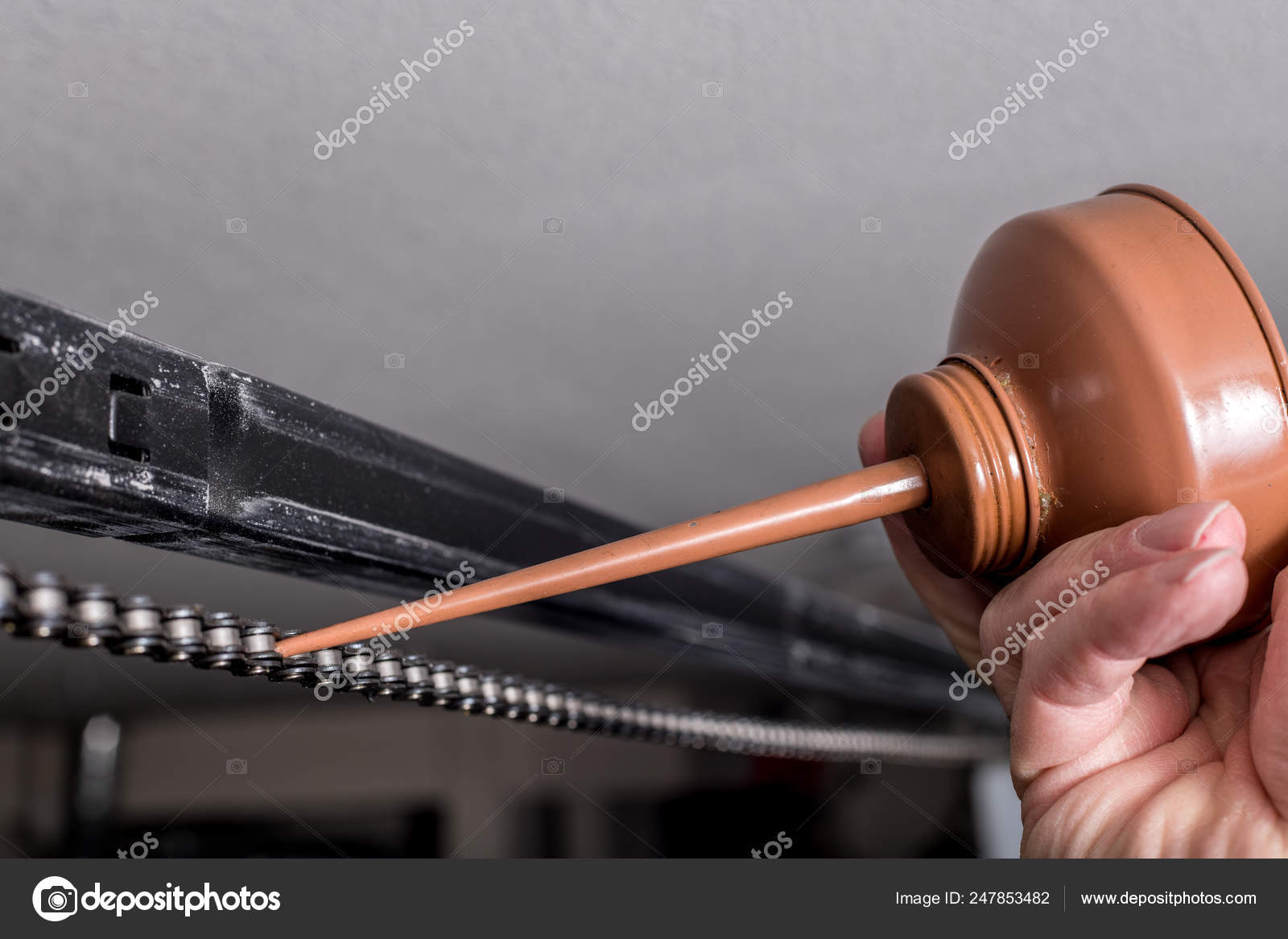 Applying A Drop Of Oil To A Chain That Belongs To A Garage Door