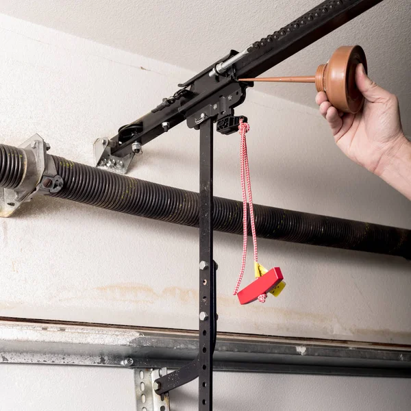 Man oils the quick release of a garage door opener to keep it wo — Stock Photo, Image