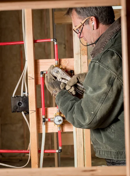 Master fontanero trabaja en algunas tuberías modernas en la nueva construcción de viviendas — Foto de Stock