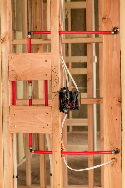 Caixa elétrica com fio áspero perto de alguns tubos vermelhos modernos de encanamento — Fotografia de Stock