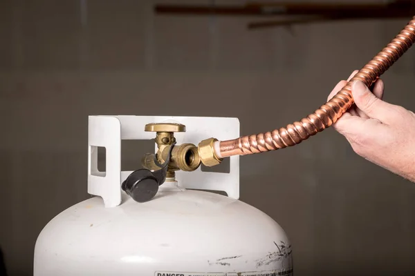 El hombre trata de encajar un tubo de cobre en una botella de propano — Foto de Stock