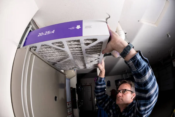 Handyman replaces the filter in the hot air furnace at a home — Stock Photo, Image