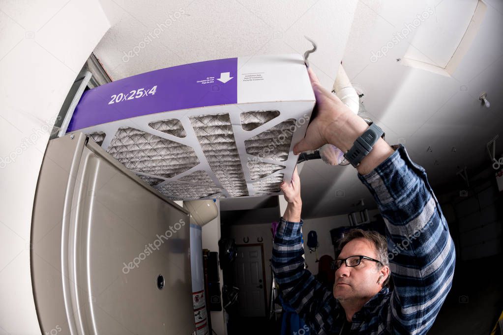 Handyman replaces the filter in the hot air furnace at a home