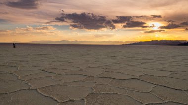 Spectator watches the sun set over the salt flats in Utah with c clipart