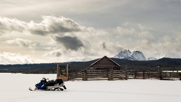 Moto de nieve estacionado en un viejo corral de Idaho en invierno con diente de sierra — Foto de Stock