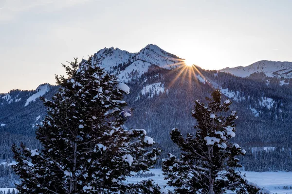 Sun star peaks from behind a mountain on a winters evening in Id