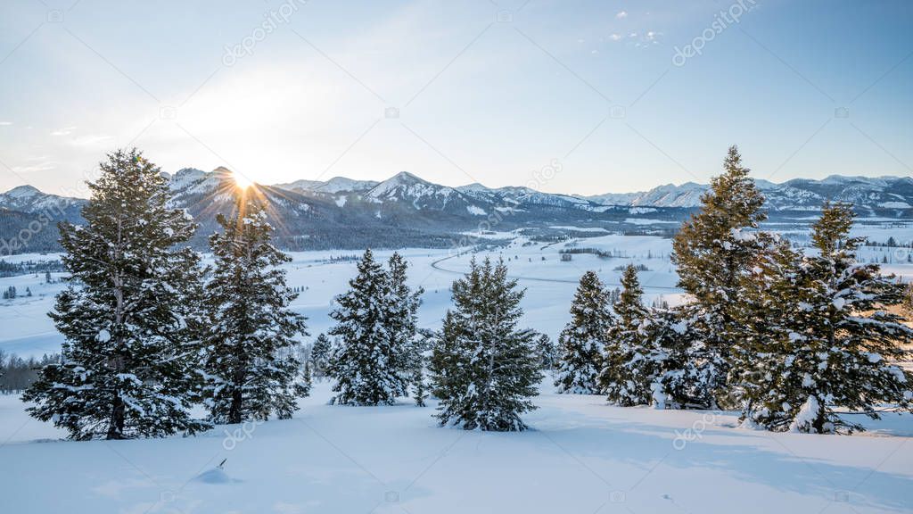 Last rays of evening sun shine on a winter valley covered with s