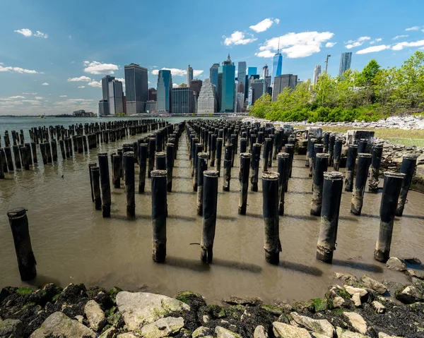 Low tide with pylons and New York City across the water — Stock Photo, Image