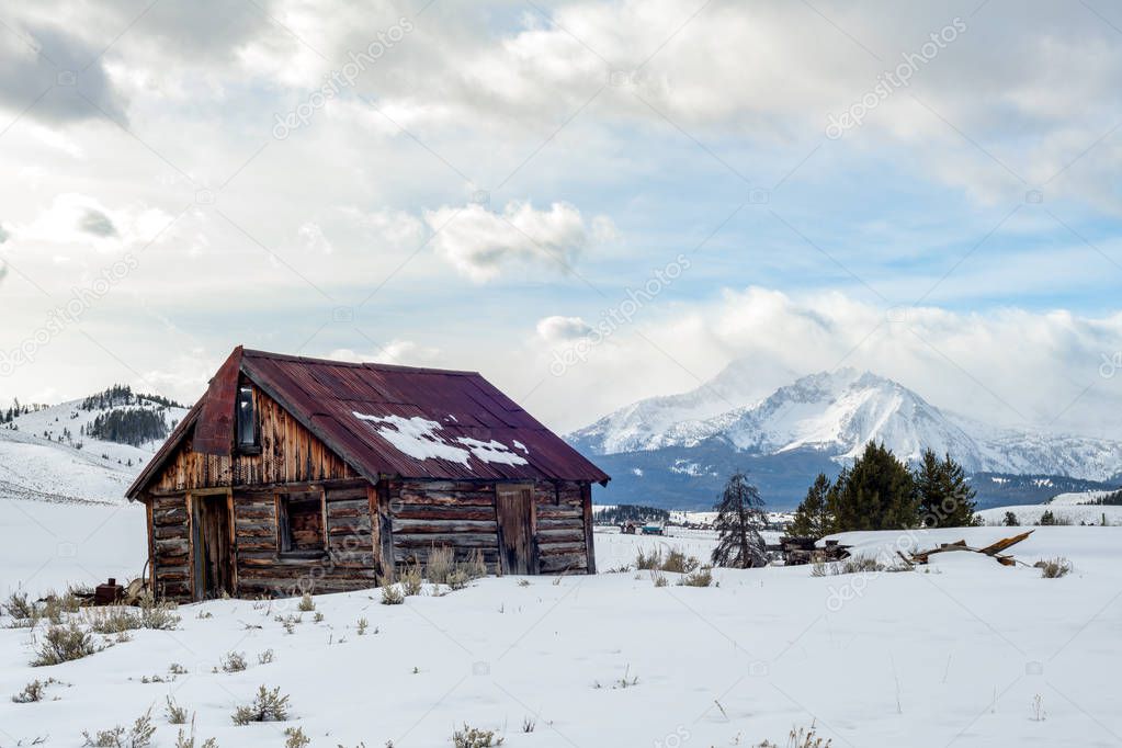 Rickety old cabin new Stanley Idaho in winter with Sawtooth Moun