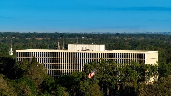 A federal building amongst trees with American flag flying in th