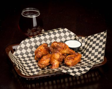 Bir bardak bira ile bir sepet içinde birkaç tavuk kanatları