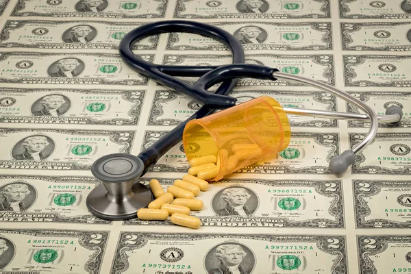 Sheet of US currency with a stethoscope on with some pills — Stock Photo, Image