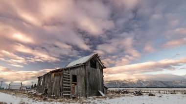 Üzerinde sabah renkli bulutlar ile kışın Çiftlik ahır