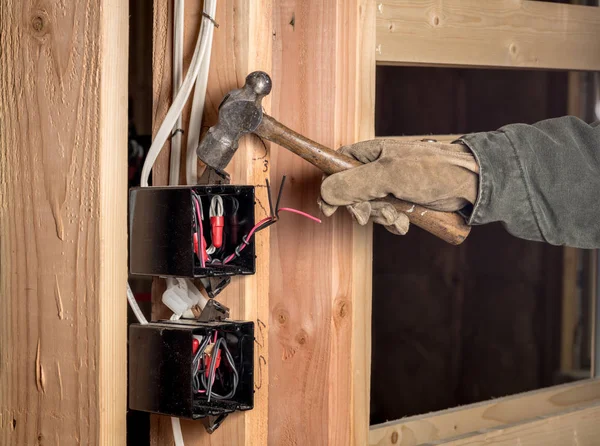 Építőipari munkás kalapácsok az épület elektromos dobozán — Stock Fotó