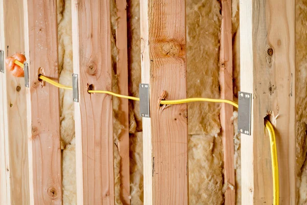 Sárga huzal táplálja keresztül fából készült szegecsek az új otthon építése — Stock Fotó