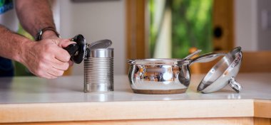 Preparing a meal by first opening a metal can clipart