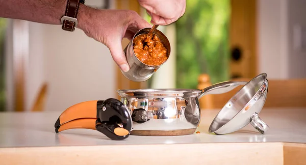 Homem tira chili de uma lata de metal em uma panela — Fotografia de Stock