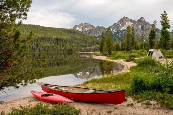 Kleine rode boten langs en Idaho Lake met tent en berg — Stockfoto