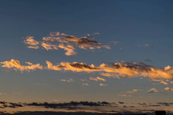 Nubes anaranjadas contra un cielo azul profundo con la cálida luz de moro — Foto de Stock