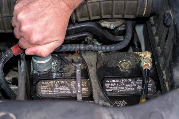 Homem limpa os terminais de uma bateria em um caminhão — Fotografia de Stock