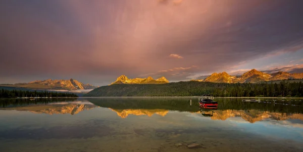 朝の光が高い山頂に当たるように湖のボート — ストック写真