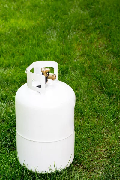 Single propane bottle sitting in the grass with warning labels — Stock Photo, Image