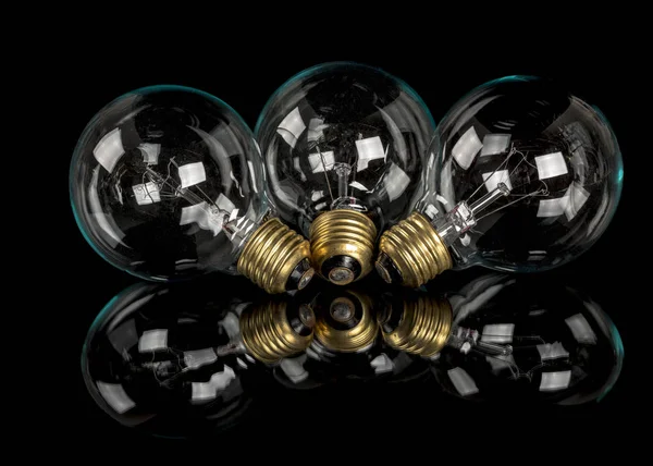 Trois ampoules incandescentes en verre posées sur une table noire — Photo