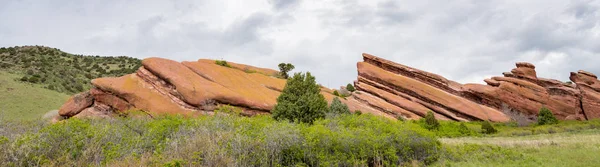 Formação única de rocha vermelha com arbustos verdes e nuvens — Fotografia de Stock