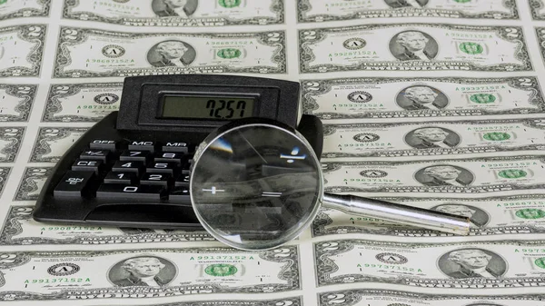 Money and a calculator with a magnifying glass — Stock Photo, Image