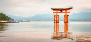 Japon Torii ve bulutlu bir günde okyanusta yansıması