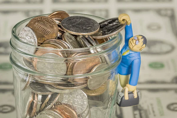 Jar filled with coins with and man hangs on — Stock Photo, Image