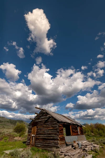 Velha cabine de madeira em ruínas em Idaho com céu azul e nuvens brancas ove — Fotografia de Stock