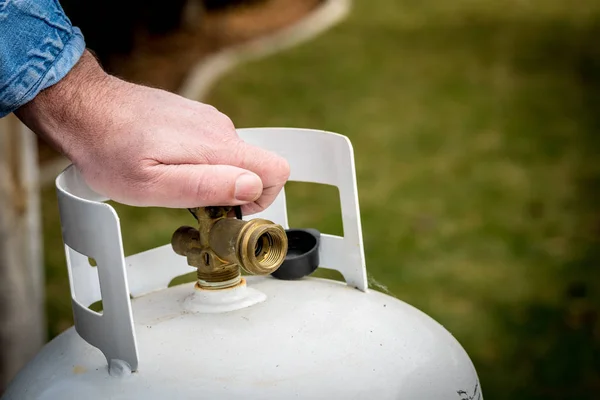 Man closes a knob on a propane tank — Stock Photo, Image