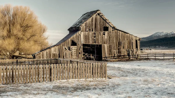 山や森と日の出の冬に農家の納屋 — ストック写真
