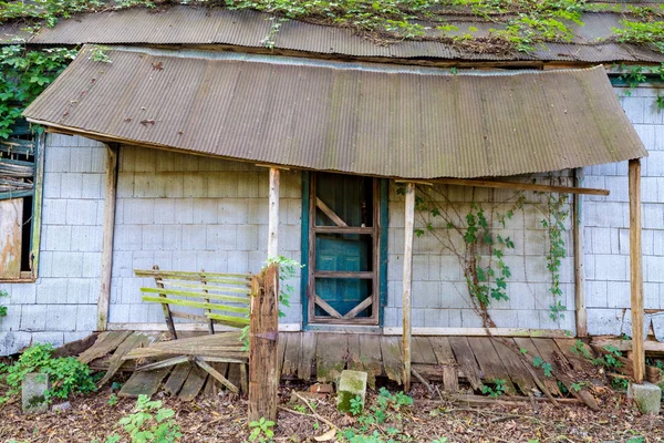 Dilapidated house falling down in a forested community — Stock Photo, Image