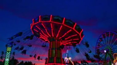 Gün batımında salıncak koltuklar ve spin ile ilçe fuarında Karnaval yolculuğu