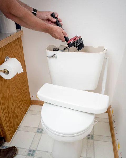 Man works on a toilet and replaces part — Stock Photo, Image